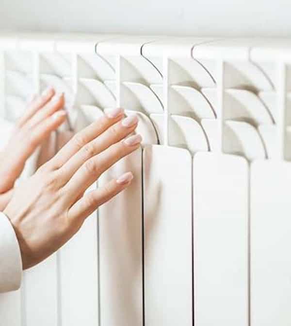 Zwei Hände an einer Heizung nach hydraulischem Abgleich von Steinkühler in Leverkusen.