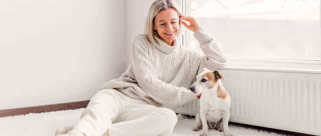 Frau sitzt zufrieden mit ihrem Hund an der warmen Heizung Dank des Licht und Steuerung System von Steinkühler in Leverkusen.