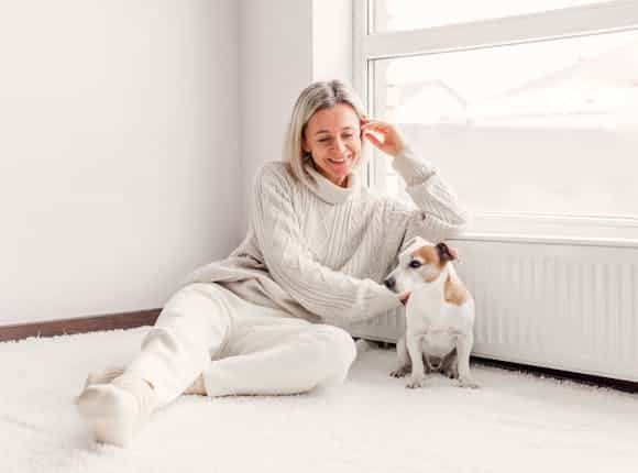 Frau sitzt zufrieden mit ihrem Hund an der warmen Heizung Dank des Licht und Steuerung System von Steinkühler in Leverkusen.